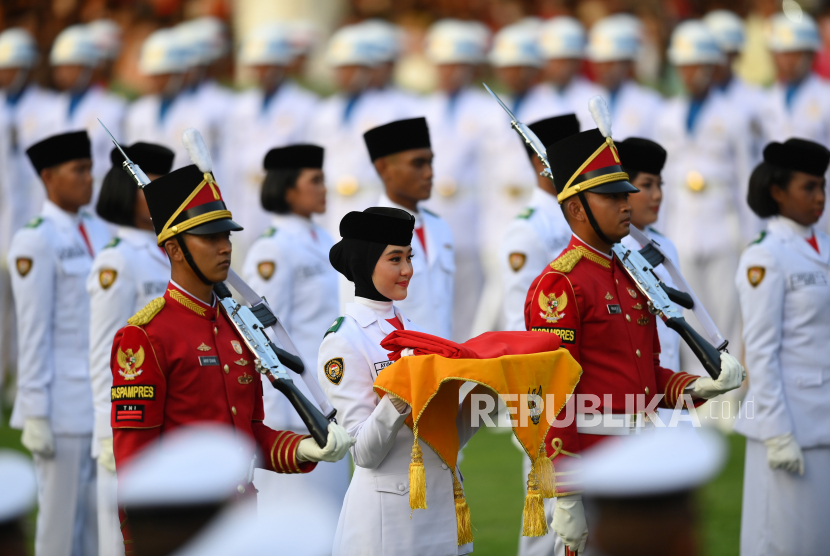 Anggota Paskibraka Ayumi Putri Sasaki (tengah) membawa bendera Merah Putih usai diturunkan dalam Upacara Penurunan Bendera Sang Merah Putih dalam rangka HUT ke-77 Kemerdekaan RI di Jakarta, Rabu (17/8/2022). HUT ke-77 RI tersebut mengangkat tema Pulih Lebih Cepat, Bangkit Lebih Kuat.